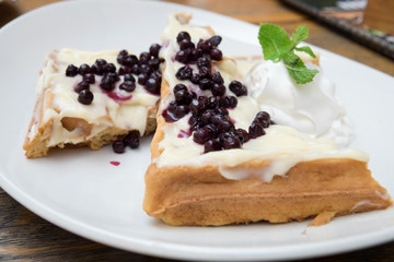 Delicious traditional Belgian homemade waffles with sweet vanilla sauce, fresh blueberries and whipped cream served at the confectionery of Novi Sad, Serbia