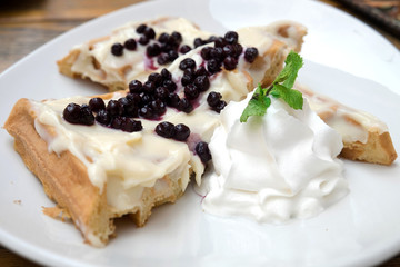 Delicious traditional Belgian homemade waffles with sweet vanilla sauce, fresh blueberries and whipped cream served at the confectionery of Novi Sad, Serbia