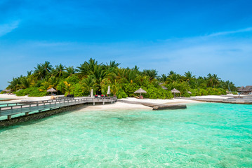 A peer to the paradise island with green palms and snow-white sand beach 