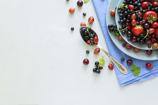 Fruit salad with strawberry, blueberry, cherry, gooseberry and black currant on wooden gray background. Flat lay. Top view