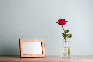 Empty photo frame and a rose in a vase