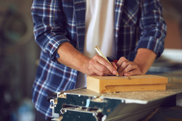 Carpenter measuring a wooden plank in a carpentry shop