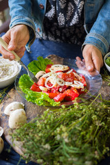 Woman hands holds vegetables salad with ripe red tomatoes and onion rings on big green salad leaves. Served with Israeli chickpea hummus spread with sesame seeds tahini. Raw vegan vegetarian food