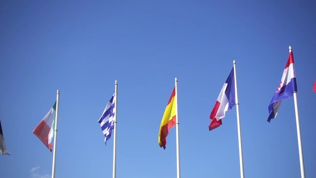 Flags of European countries of Ireland, Spain, Greece, Fance and Croatia against the blue sky. Smooth slowmotion from a 120 fps original shoot
