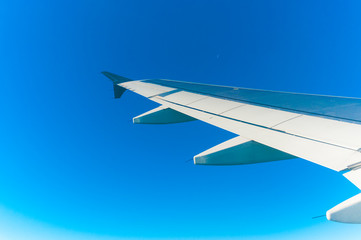 Fototapeta na wymiar Airplane wing in the clean blue sky