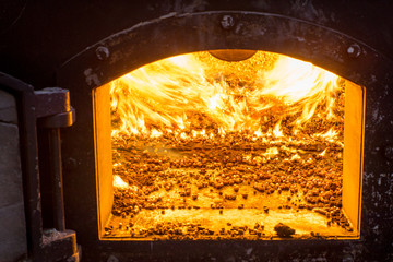 Burning bio pellets fuel in the boiler. Economical, ecologicla fuel. - obrazy, fototapety, plakaty