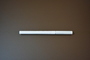 White thin cigarette with XS filter on a matte brown background