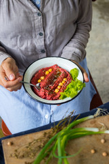 Woman hands holds spicy red beetroot Israeli chickpea hummus with herbs and covered with olive oil. Traditional mediterranean food used with vegetables. Vegan vegetarian healthy food.