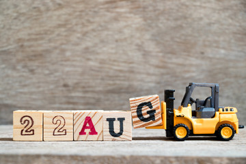 Toy forklift hold block G to complete word 22 aug on wood background (Concept for calendar date in month August)