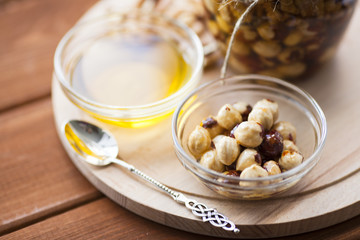 Natural honey and nuts in glass jars, vintage silver spoon on the wooden background. Healthy food, diet, lifestyle concept. Top view. Close up.