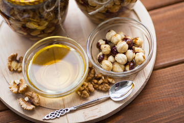 Natural honey and nuts in glass jars, vintage silver spoon on the wooden background. Healthy food, diet, lifestyle concept. Top view. Close up.