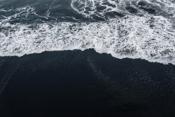 écume blanche de l& 39 océan sur la texture volcanique du sable noir