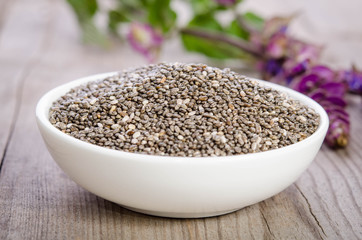 Chia seed healthy superfood in bowl with flower over wooden table