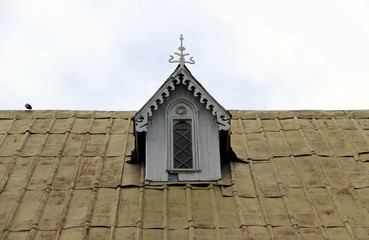 Wooden attic window on the roof with sky background.