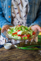 Raw vegan zucchini spaghetti. Yummy fresh summer salad  with red bell pepper, tomatoes, cucumbers and salad leaves garnished and dressed with sesame seeds and homemade tahini dip sauce paste. 