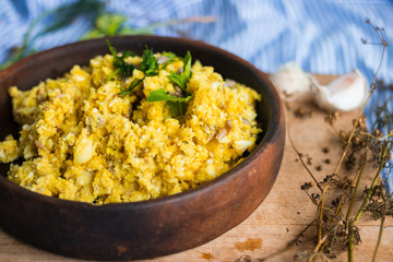Vegan raw cauliflower rice porridge mixed and dressed with turmeric powder, spices and green herbs. Raw vegan vegetarian healthy food. Raw foodist lunch or dinner