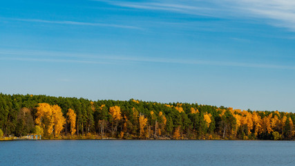 Panorama of the lake with autumn mixed forest on the sides