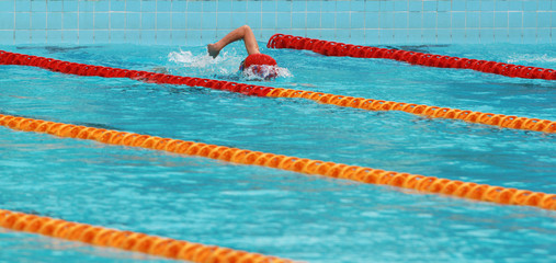 Swimmer swims free style, front crawl or forward crawl stroke in a swimming pool for competition or...