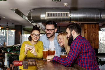 Group of four friends taking selfie by mobile phone on cafe and smile