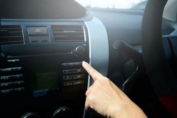 the index finger of women press on the button at the control panel for play music in car