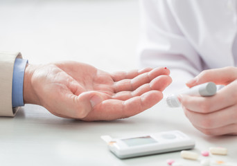 man measures sugar level with a glucometer