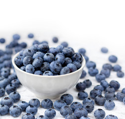 Ripe bluberries in bowl on white wooden table