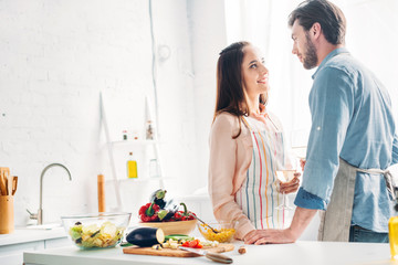 couple holding wineglasses and looking at each other in kitchen