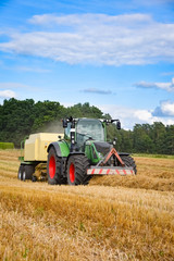 Fototapeta na wymiar Strohernte - Traktor mit Strohpresse, Hochformat