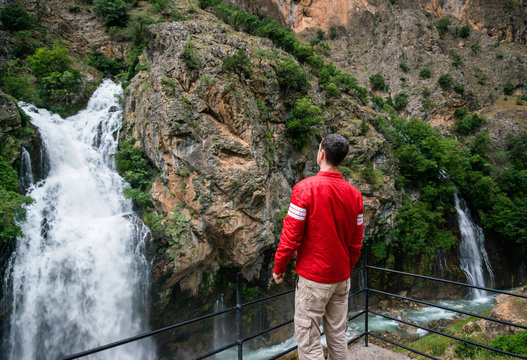 Traveler looking at powerful waterfalls in mountains