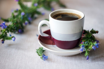 A cup of coffee and a meadow flowers