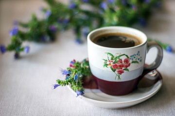 A cup of coffee and a meadow flowers