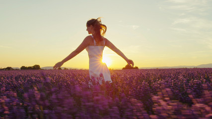 SLOW MOTION: Young woman running through lavender field at sunset