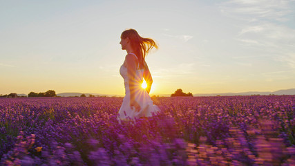SLOW MOTION: Young woman running through lavender field at sunset