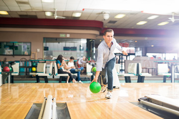 Dedicated Teen Playing Bowling With Green Ball In Club
