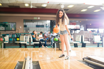 Naklejka na ściany i meble Teenage girl having fun in a bowling alley