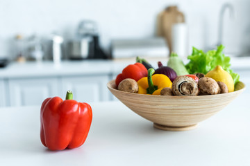 close-up view of bell pepper and bowl with fresh vegetables on kitchen table