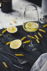 Wine glasses of home lemonade for italian dinner with pasta and peper on the grey wooden background and two kind of textile