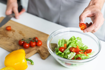 cropped shot of man in apron cooking vegetable salad