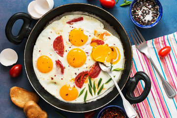 Fried eggs with cherry tomatoes in a pan. Fresh and hearty Breakfast. The view from the top.