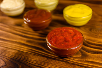 Different sauces in glass bowls on wooden table