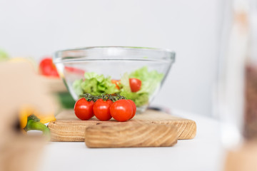 selective focus of glass bowl and fresh vegetables on wooden cutting board