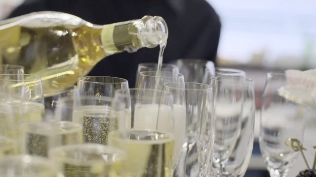 Many beautiful champagne in flutes standing on table in slow motion.