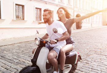 Fototapeta na wymiar Happy young couple having fun on a scooter