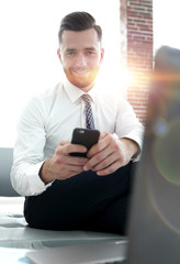 businessman holding a smartphone and looking at the camera
