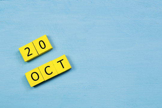 OCT 20, yellow cube calendar on blue wooden surface with copy space