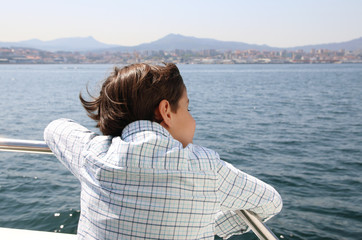 ni&ntilde;o en un barco contemplando el mar