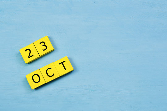 OCT 23, yellow cube calendar on blue wooden surface with copy space