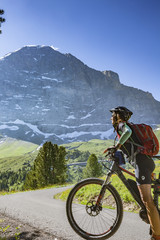 Fototapeta premium nice and ever young senior woman riding her e-mountainbike below the Eiger Northface near Grindelwald and Wengen, Jungfrauregion, Switzerland