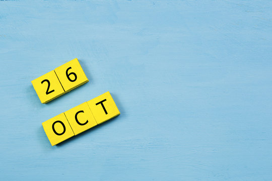 OCT 26, yellow cube calendar on blue wooden surface with copy space