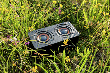 close-up of a portable audio speaker in the grass, freedom of movement listening to music outdoors to relax and have fun